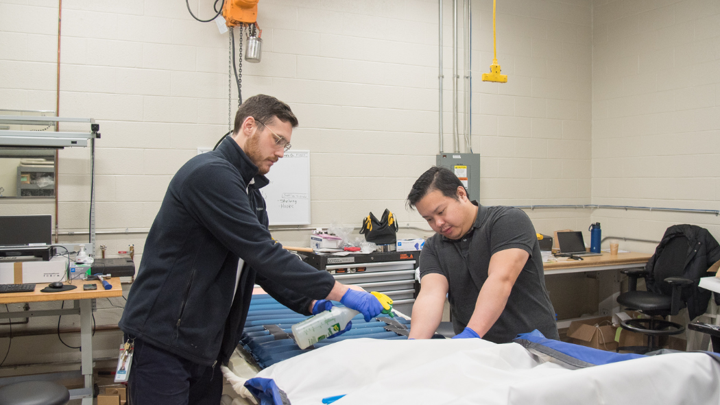 two technicians work on patient bed