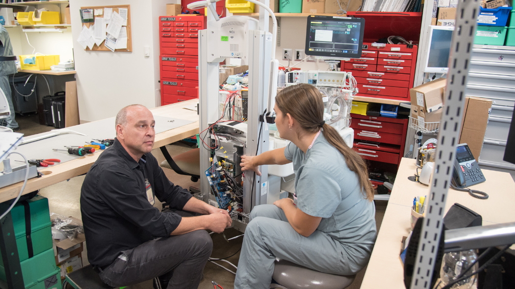 two technologists work on piece of equipment