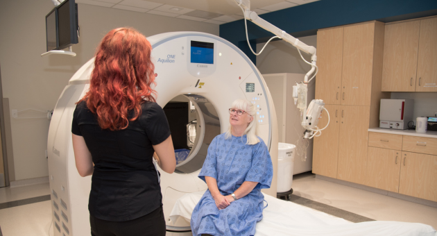 A CT technologist explains the scan to a patient.