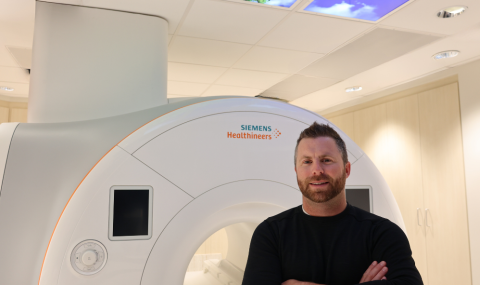 MRI technologist stands in front of a scanner