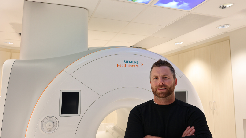 MRI technologist stands in front of a scanner