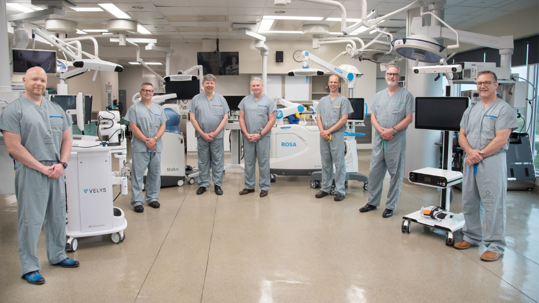 LHSC Surgeons standing around 4 ortho robots used for surgery