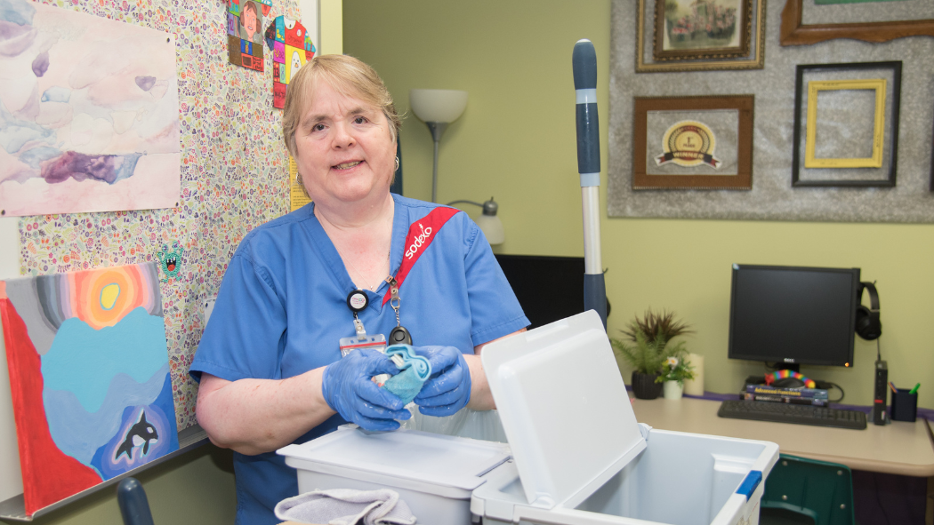 Housekeeper stands behind cleaning cart