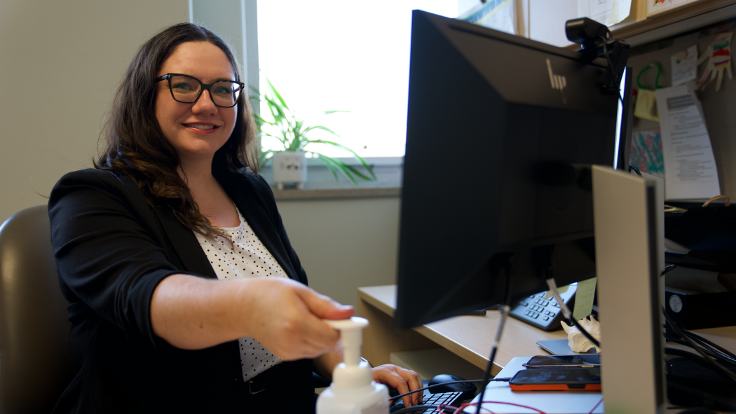 staff member smiles at camera while using alcohol based hand rub